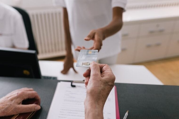 Ein Patient zeigt seine Krankenversicherungskarte in einer Arztpraxis.