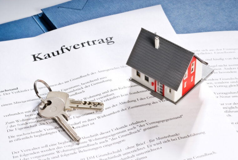 Eine Nahaufnahme zeigt den Kaufvertrag eines Hauses inklusive Schlüssel.