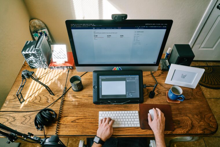 Arbeitnehmer sitzt am Schreibtisch und benutzt computer und tablet im home office