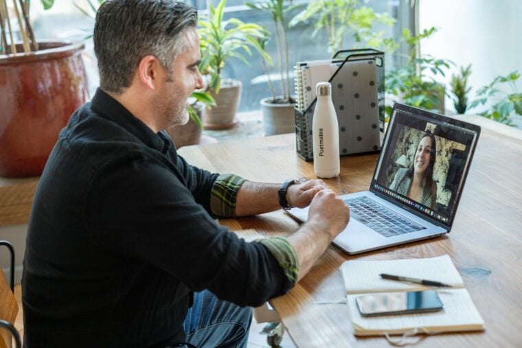 Ein Mann sitzt am Schreibtisch und ist am Laptop in einem Meeting