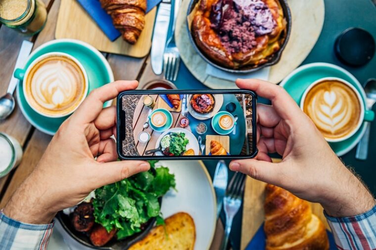 Influencer*in macht ein Foto vom Essen im Restaurant, um mit dem daraus entstehenden Post Geld zu verdienen.