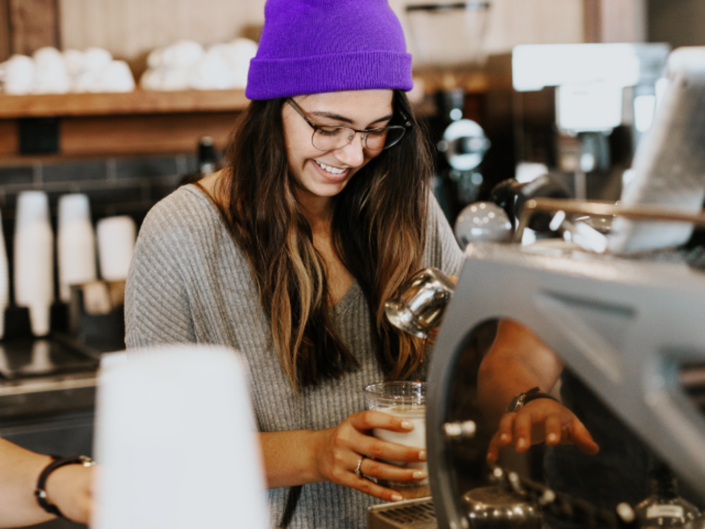 Eine junge Frau arbeitet als Baraushilfe in einem Café.