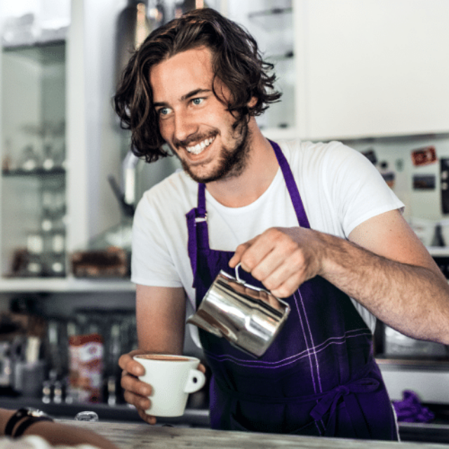 Das Bild zeigt einen jungen Mann, der sich als Barista etwas Geld in den Semesterferien dazu verdient.