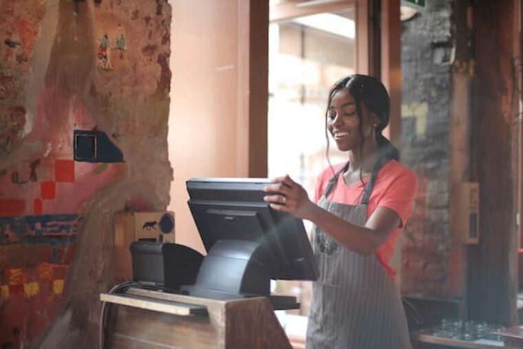 Was ist Zeitarbeit? Im Bild steht eine Arbeitsnehmende im Café an der Kasse.