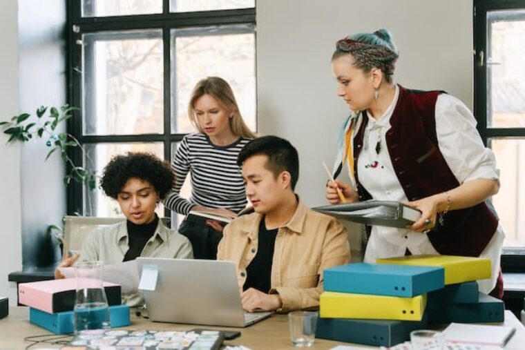 Ein Gruppe von jungen Arbeitehmenden sitzen an einem Tisch. Sie arbeiten in Zeitarbeit.