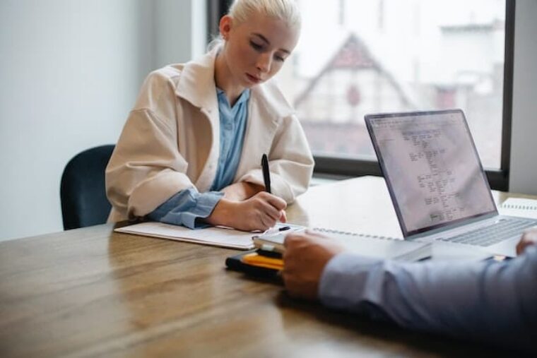 Eine Arbeitnehmende unterschreibt einen Arbeitsvertrag im Rahmen der Zeitarbeit.