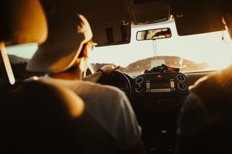 Mit Autofahren Geld verdienen. Das Bild zeigt einen Autofahrer und Beifahrer aus der Rücksitzperspektive.