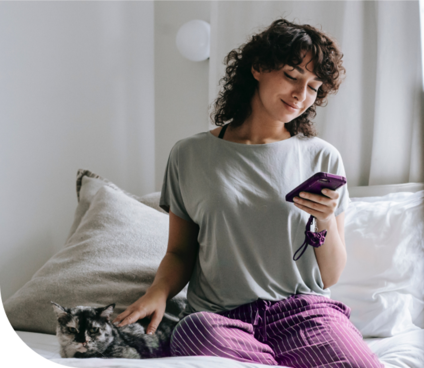 Das Bild zeigt eine junge Dame, die auf dem Bett sitzt und ihre Katze streichelt. Sie hält ihr Smartphone, um das Onboarding bei Zenjob zu absolvieren.