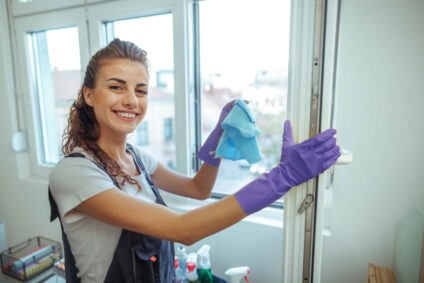 Studentin putzt die Fenster eines Gebäudes