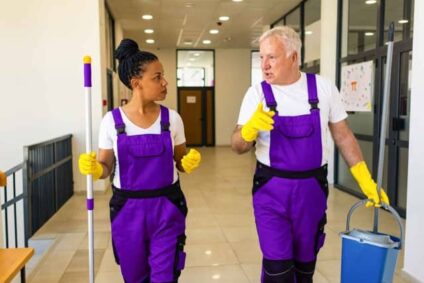 aushilfe studentische hilfskraft des reinigungsteams und erwachsener gehen in einem flur gebäudedienstleistungen
