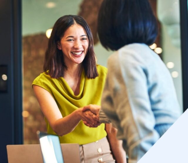 Zwei Frauen schütteln sich die Hand