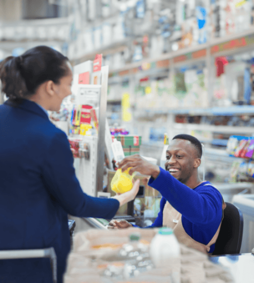 Junger Kassierer gibt einer Kundin das Wechselgeld