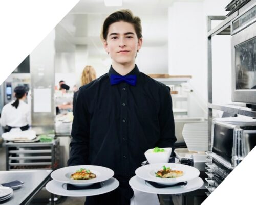 Ein Student in schwarzer Kleidung hält Teller, um sie zu servieren