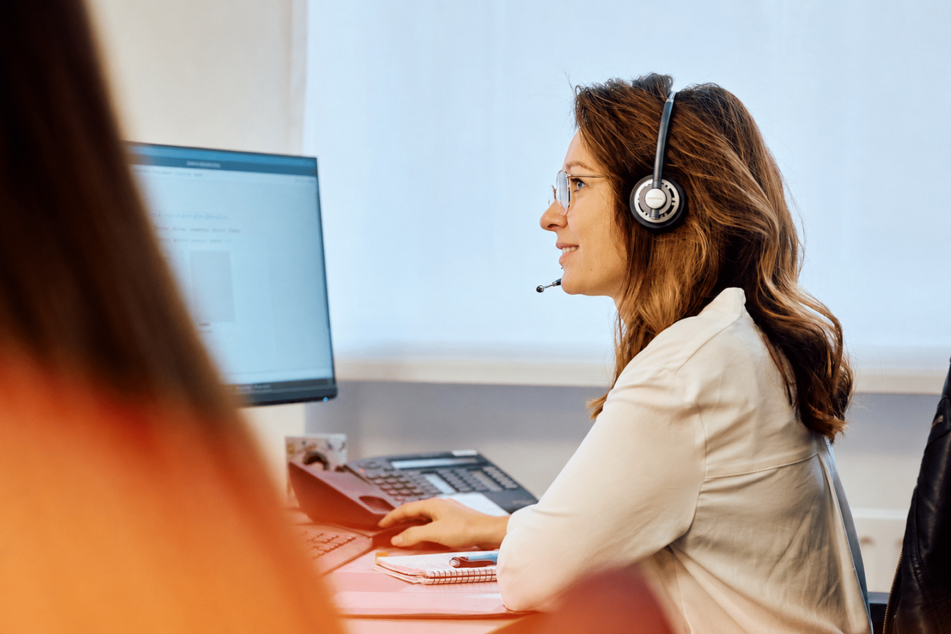 Customer Support Agentin sitzt am Laptop mit Headset