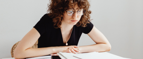 young woman sitting at desk checking her CV