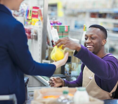 The image shows a young man working as a cashier.