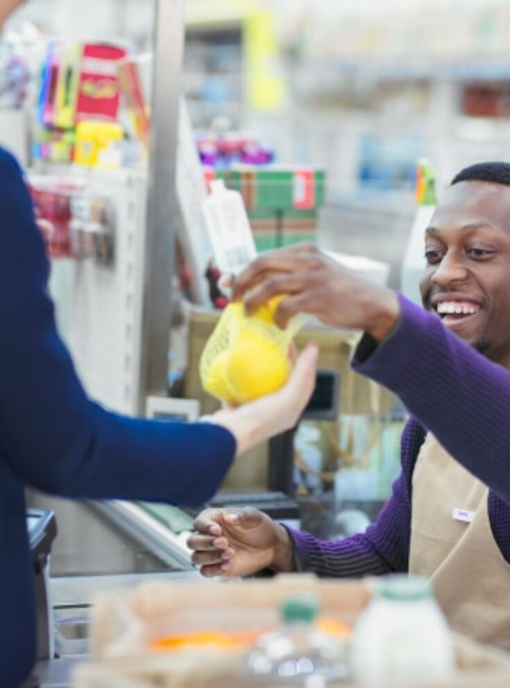 The image shows a young man working as a cashier.